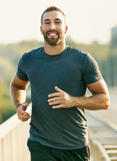 Smiling man jogging outdoors on sunny day