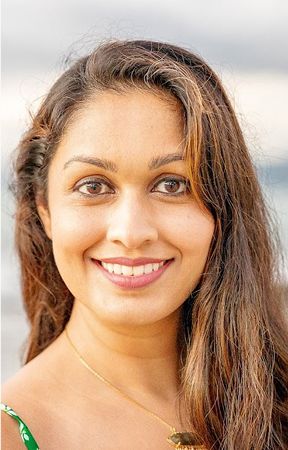 Smiling woman with long, wavy hair outdoors.