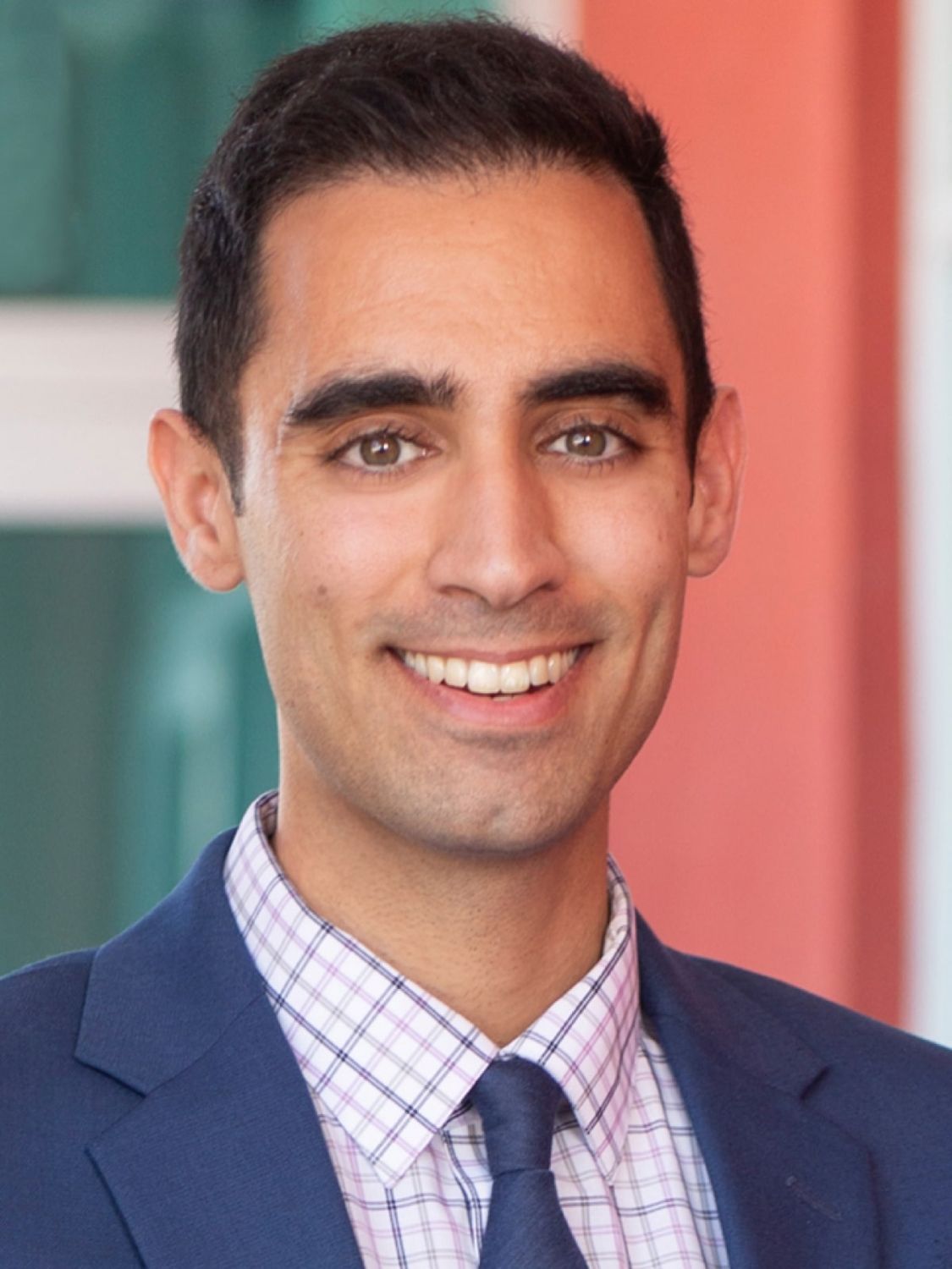 Smiling man in a suit against colorful background.