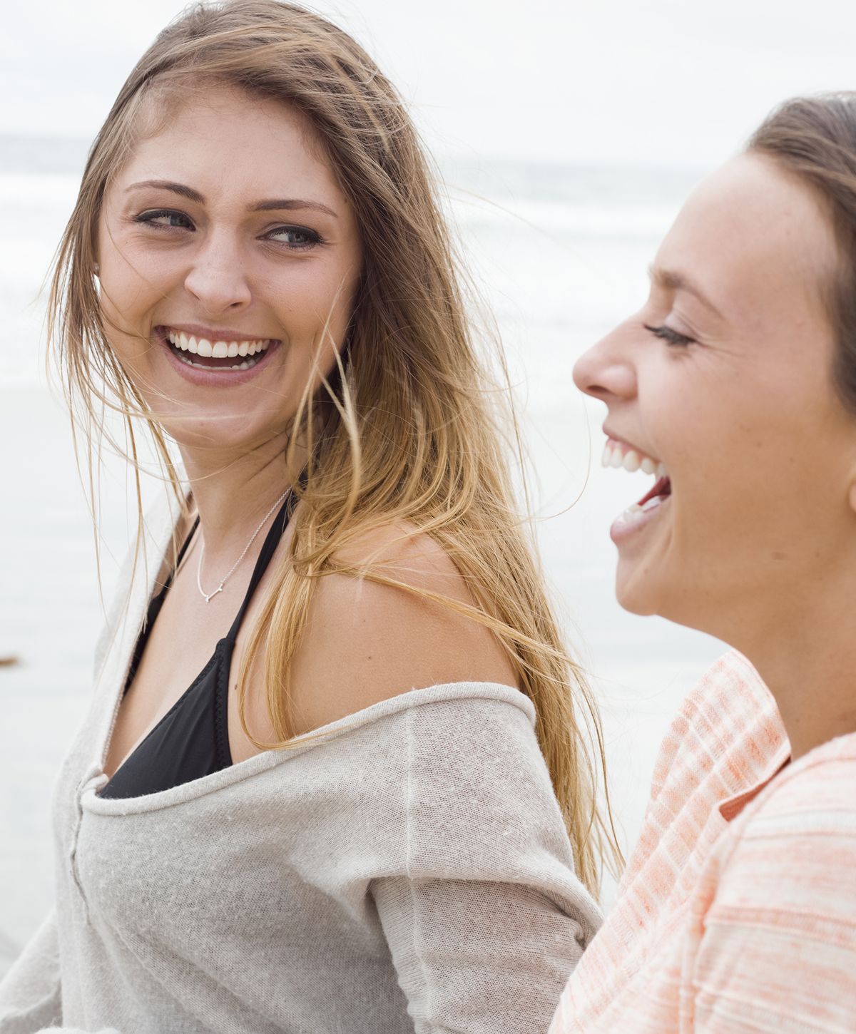 Two women laughing happily at the beach.