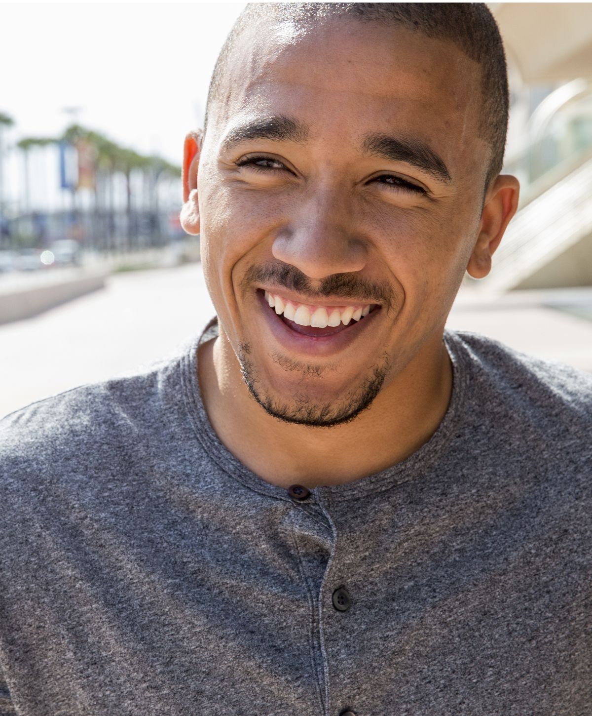 Smiling man in casual attire outdoors.