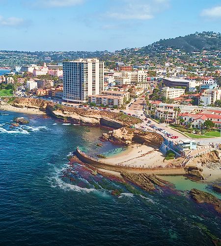Coastal cityscape with beach and rocky shoreline.