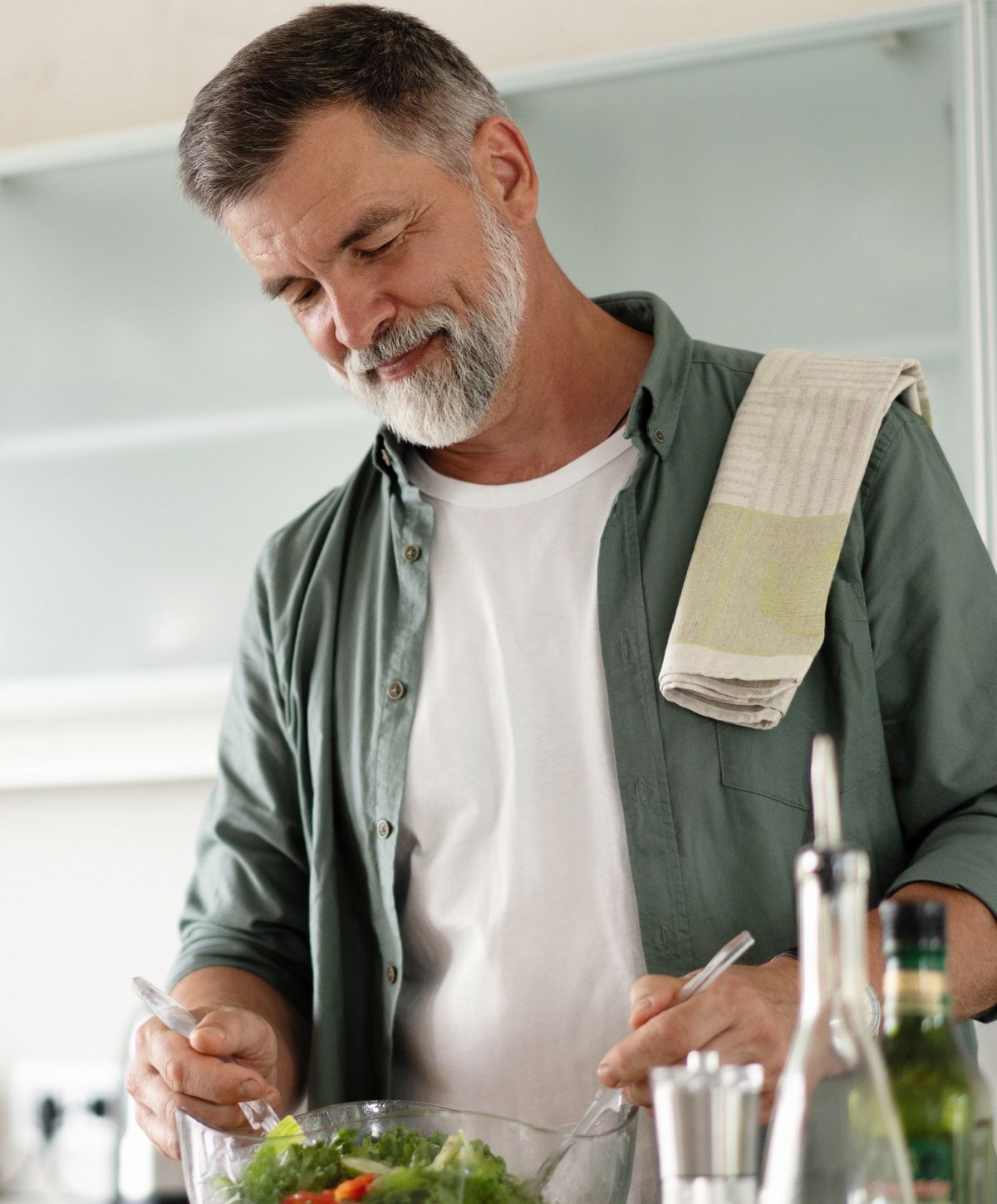 Man preparing a fresh salad in the kitchen.