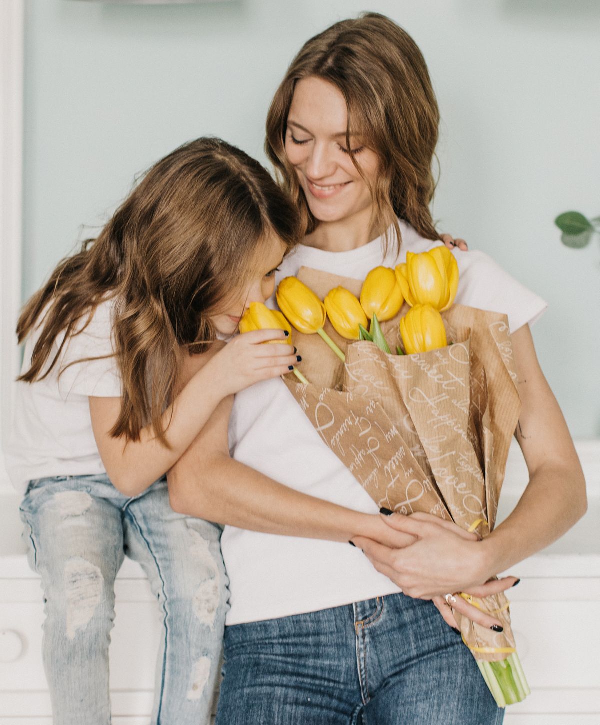 Mother and daughter with yellow tulip bouquet.