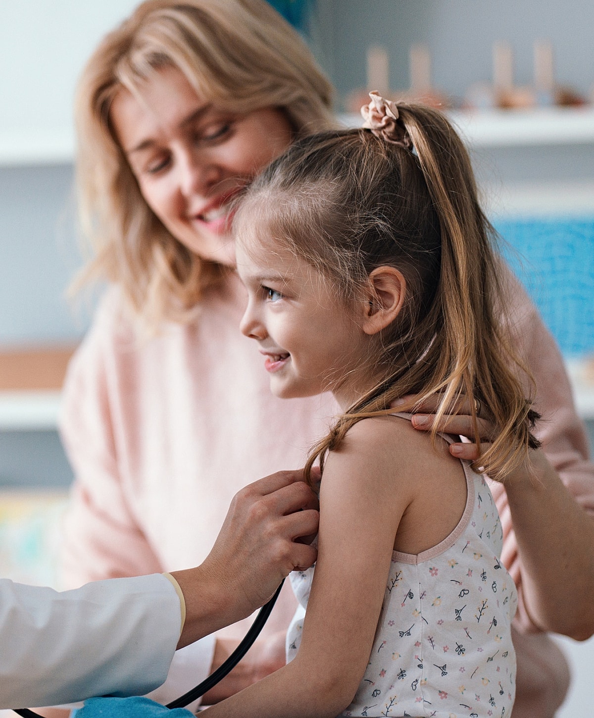 Child at healthcare visit with smiling caregiver.