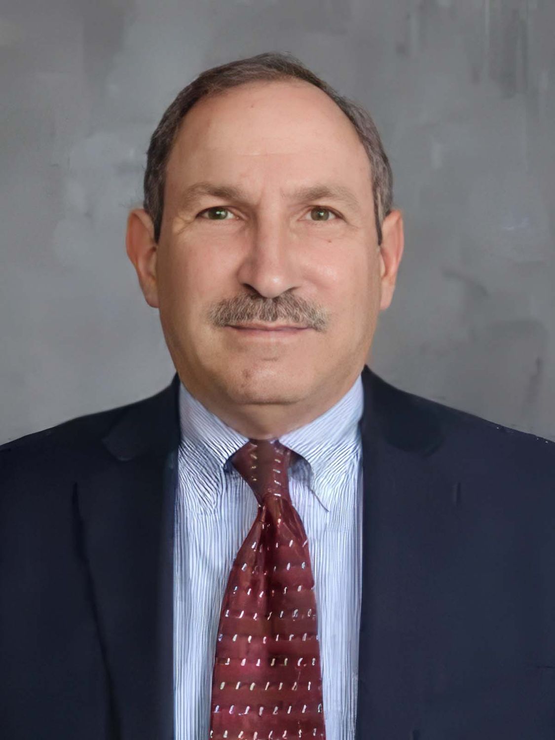 Man in suit with tie against gray background.