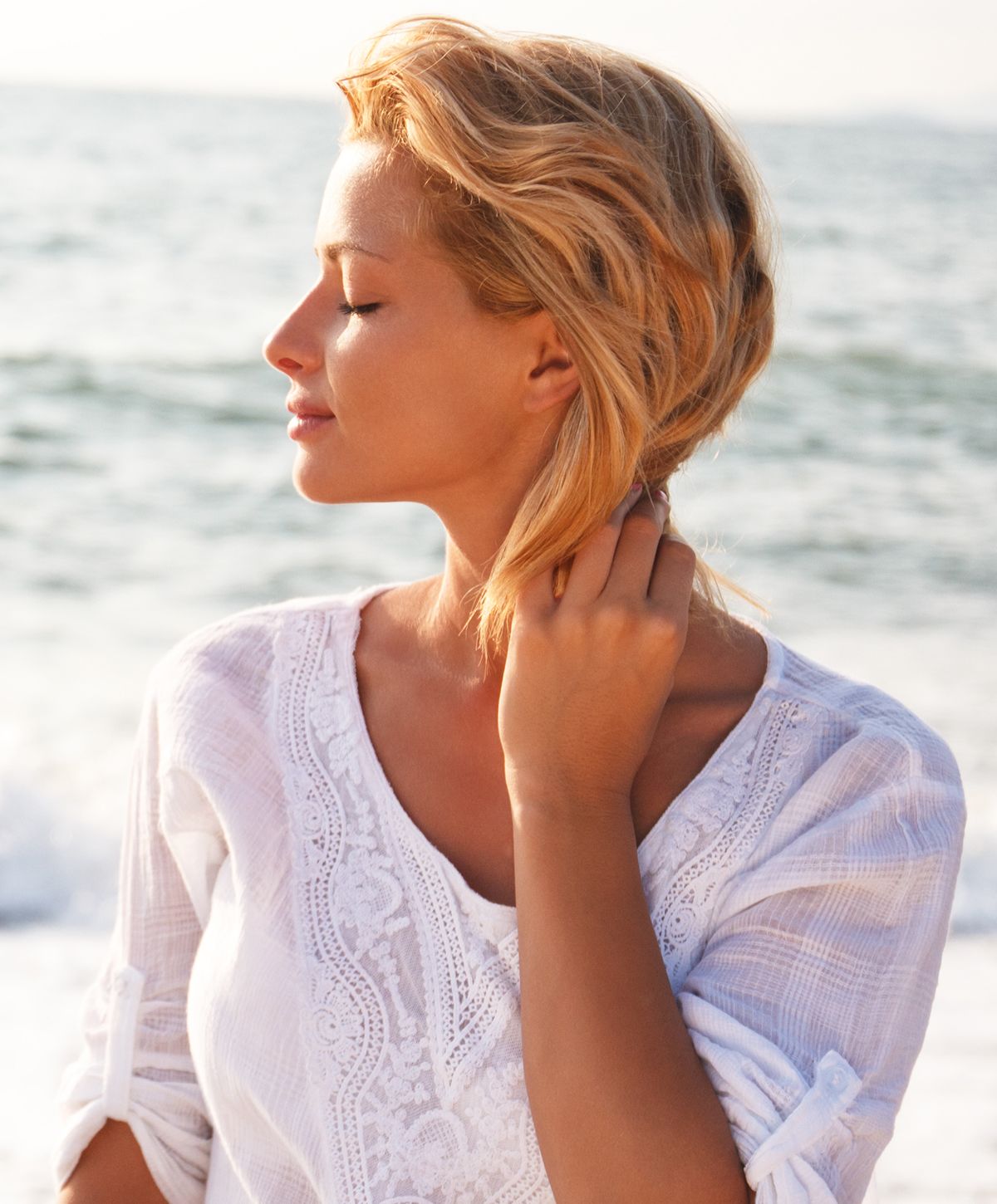 Woman by the beach enjoying the sunlight.