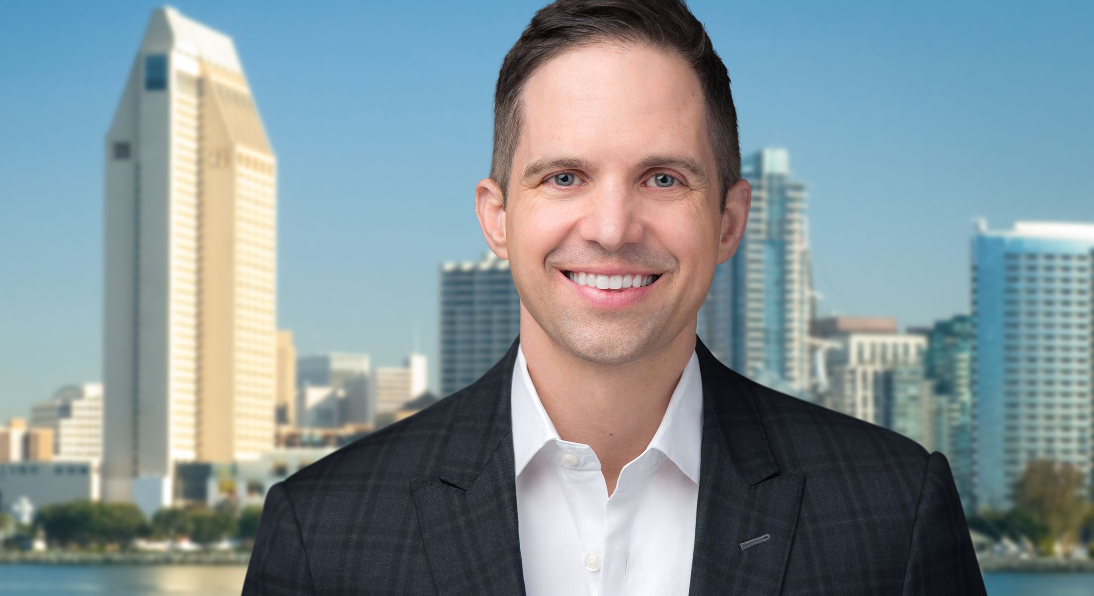 Smiling person in front of city skyline.