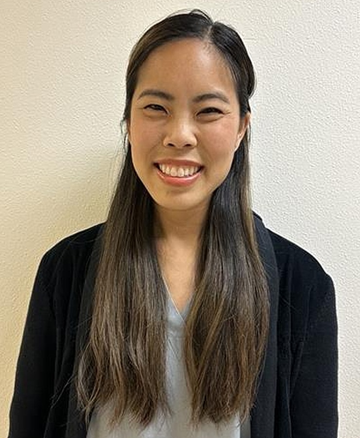 Smiling woman with long hair against plain background.