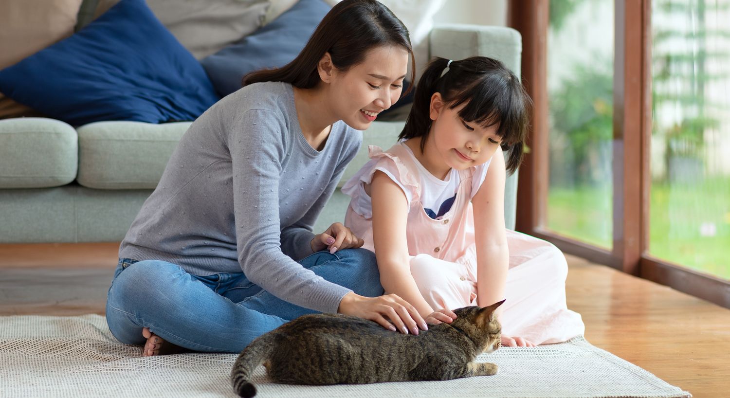 Mother and daughter playing with a cat.