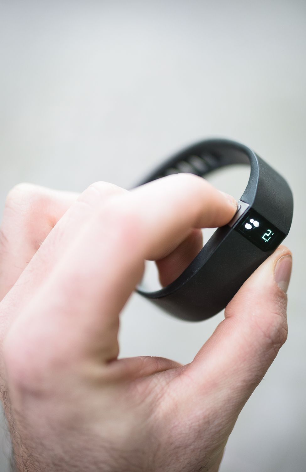 Person adjusting a black fitness tracker on wrist.