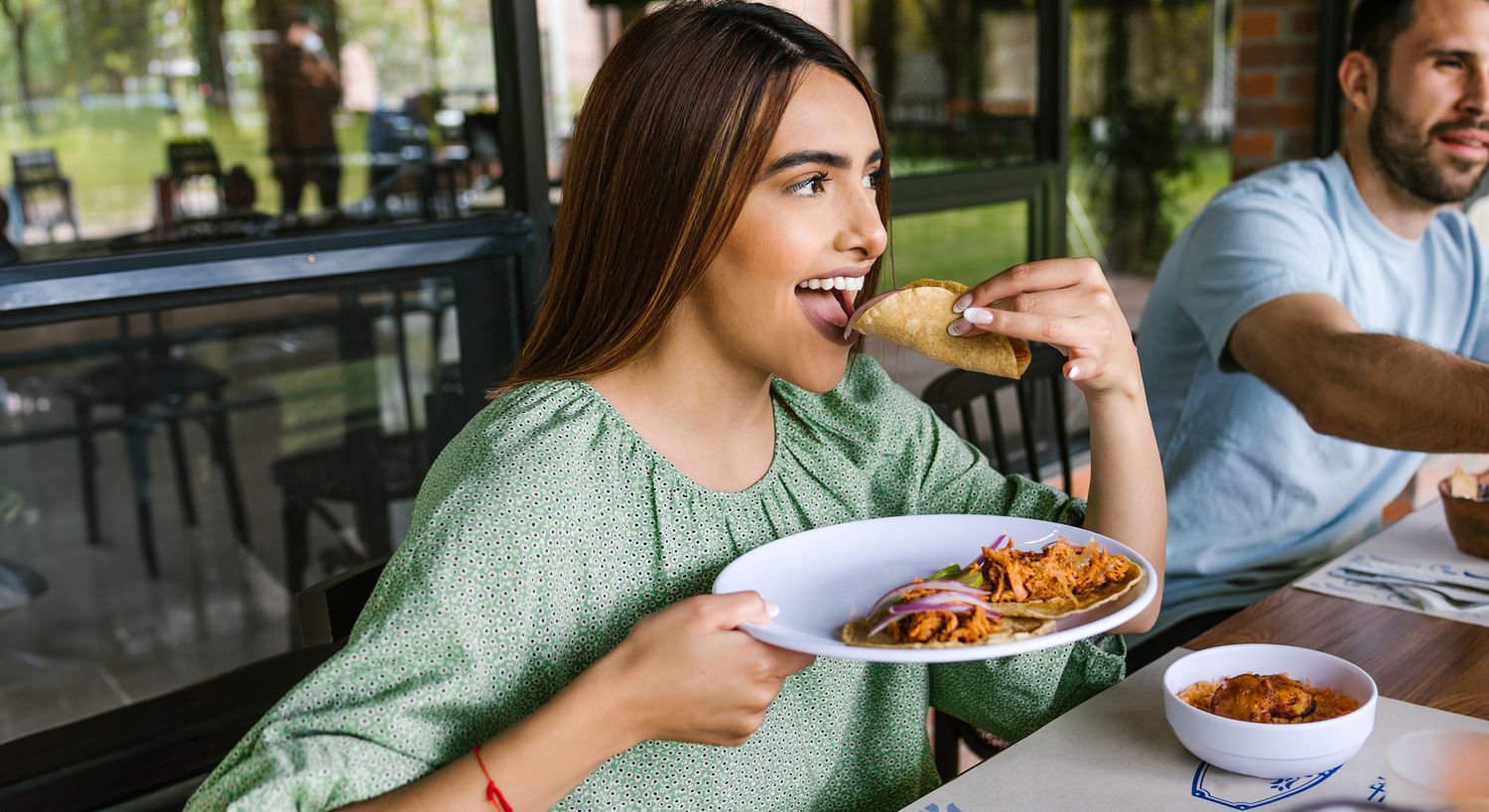 Person enjoying tacos and food at restaurant.