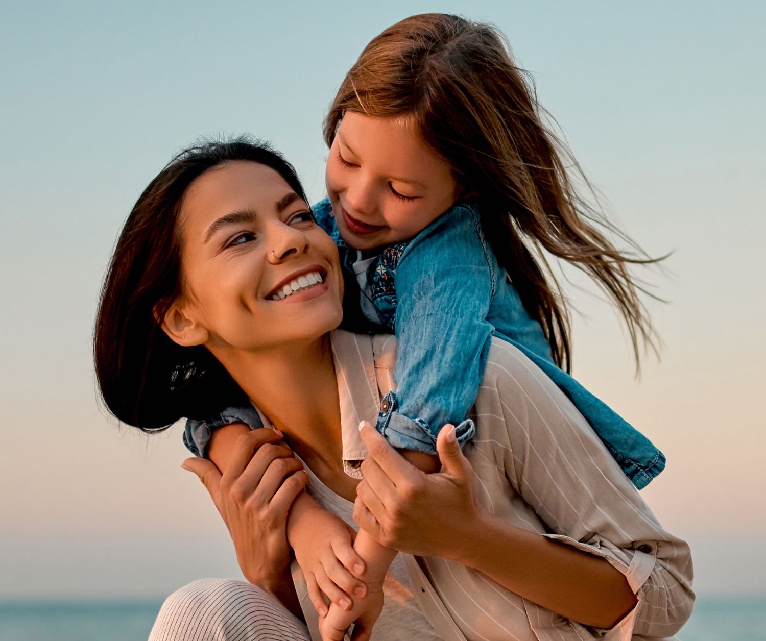 Mother and daughter playing with a cat indoors.