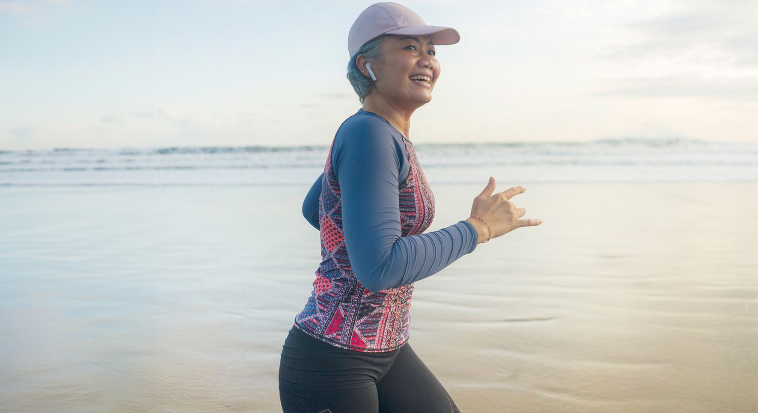 Woman jogging on beach, smiling and enjoying exercise.